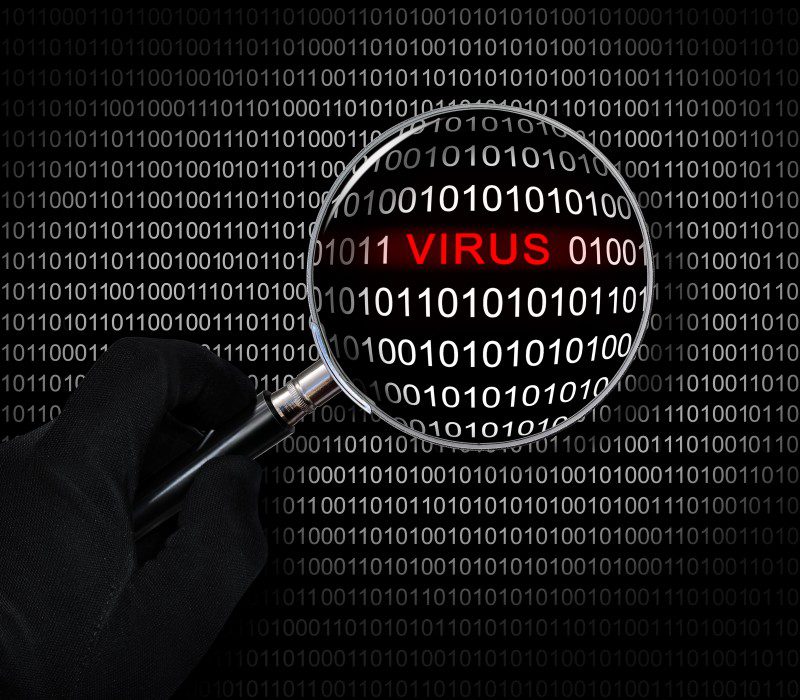 Gloved hand holding a magnifying glass over binary code